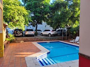 a swimming pool with cars parked in a parking lot at Terwindt Hotel in Encarnación