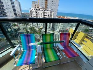 2 stoelen op een balkon met uitzicht op de stad bij Apartamento cidade ocian Praia Grande in Praia Grande