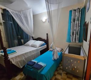 1 dormitorio con 2 camas y 1 cuna en La maison aux Orchidées, en Petit-Bourg