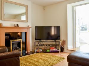 a living room with a flat screen tv and a fireplace at Ivy Cottage in Warwick