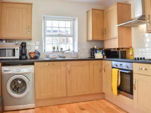 a kitchen with wooden cabinets and a washer and dryer at Ivy Cottage in Warwick