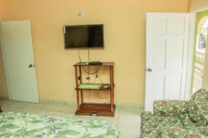 sala de estar con TV en la pared y mesa en Charlie's Cottages en Negril