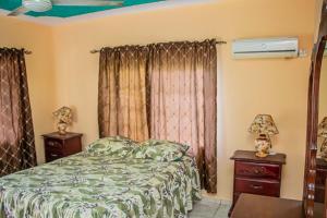 a bedroom with a bed and two night stands and a window at Charlie's Cottages in Negril
