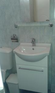 a bathroom with a white sink and a toilet at Artemis Rooms in Chora Folegandros