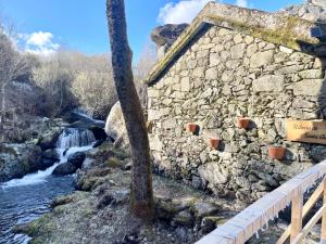 Moinho de Brião في مونتاليغري: مبنى حجري بجانب نهر به شجرة