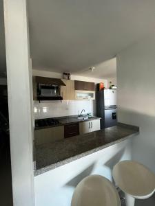 uma cozinha com um balcão com 2 cadeiras e um frigorífico em apartamento barranquilla villa campestre! em Puerto Colombia