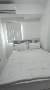 a white bed with white pillows in a room at Cibubur Village Apartemen by Ar-Ramadhan in Cibubur