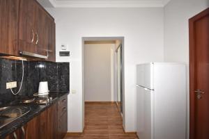 a kitchen with a white refrigerator and wooden cabinets at 74/3New building in the center of the capital in Yerevan
