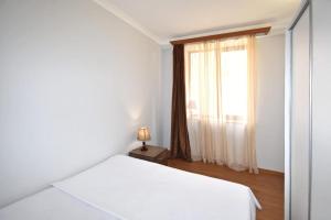 a white bedroom with a bed and a window at 74/3New building in the center of the capital in Yerevan