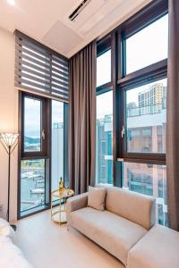 ein Wohnzimmer mit einem Sofa und großen Fenstern in der Unterkunft The Castle Ocean Marina Double Suite in Yeosu