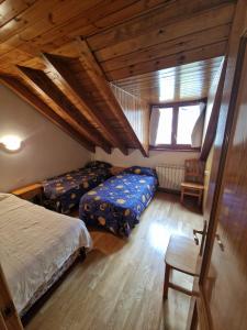 1 dormitorio con 2 camas y techo de madera en Espot Natura - Apartament de muntanya al PN Aigüestortes i Sant Maurici, en Espot