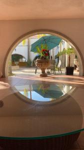 un reflejo de una fuente con un jarrón y un paraguas en HOTEL MISION SANTA MARIA en San Quintín