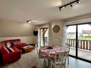 sala de estar con mesa, sofá y reloj en Les Chambres Du Vignoble en Ammerschwihr