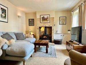a living room with a couch and a fireplace at Camside, Chipping Campden - Taswell Retreats in Chipping Campden