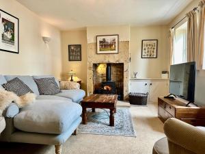 ein Wohnzimmer mit Couch und Kamin in der Unterkunft Camside, Chipping Campden - Taswell Retreats in Chipping Campden