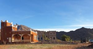 un bâtiment dans le désert avec des montagnes en arrière-plan dans l'établissement Maison AFA, à Tafraout