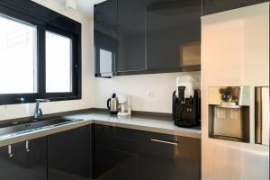 a kitchen with black cabinets and a sink and a window at Athens riviera beach villa in Anavyssos