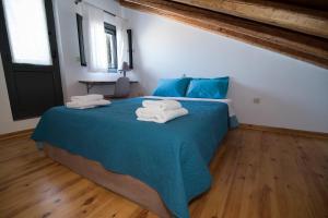 Un dormitorio con una cama azul con toallas. en Mare e Pietra, en Monemvasia
