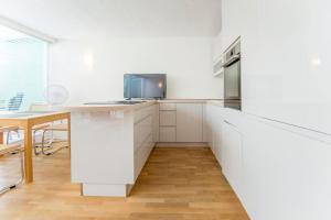 une cuisine avec des placards blancs et une télévision sur un comptoir dans l'établissement Modernes, sonniges Appartement im Herzen von Düsseldorf, à Düsseldorf