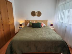una camera da letto con un letto con un piumone verde e una finestra di Cozy Island Apartment RAAL 1096 - Free Parking a Ponta Delgada