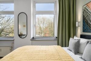 a bedroom with a large bed and two windows at BRIGHT Dortmund City Center in Dortmund