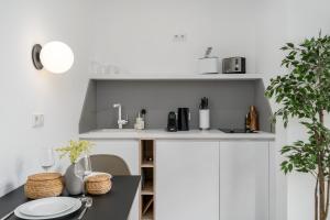 uma cozinha com armários brancos e uma mesa com pratos em BRIGHT Dortmund City Center em Dortmund