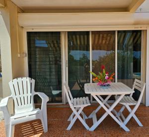 two white chairs and a table on a porch at La maison aux Orchidées in Petit-Bourg