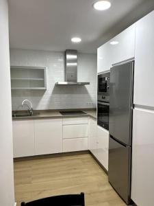 a kitchen with white cabinets and a stainless steel refrigerator at ANGELFLAT CENTRO in Ronda