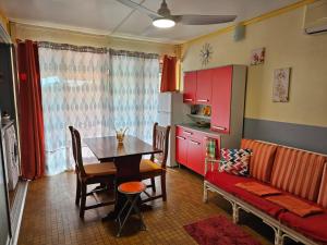 cocina con mesa y cocina con armarios rojos en La maison aux Orchidées, en Petit-Bourg