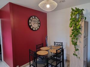 une salle à manger avec un mur rouge et une horloge dans l'établissement Gîte Pigerot, à Lucbardez-et-Bargues