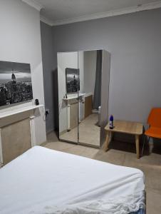 1 dormitorio con cama blanca y espejo en Court Road House, en Cardiff