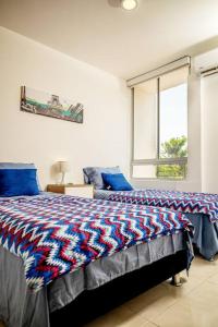 een slaapkamer met een bed met blauwe kussens en een raam bij Marquis Enclave, Condo With Pool Access and More in Ricaurte
