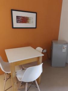 mesa, 2 sillas blancas y nevera. en La casa deMarta en Córdoba