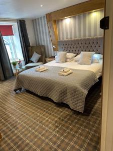 a bedroom with a large bed with two towels on it at Nithsdale Hotel in Sanquhar