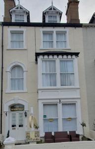 a white building with windows and chairs in front of it at St Davids & Moorfield Hotels Chapel Street in Llandudno