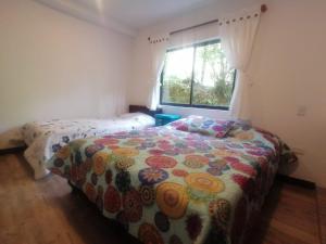 a bedroom with a bed with a flowered blanket and a window at ALOJAMIENTO EL REGALO in Salento