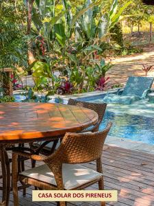 a wooden table and chairs next to a swimming pool at Casas Solar dos Pireneus in Pirenópolis