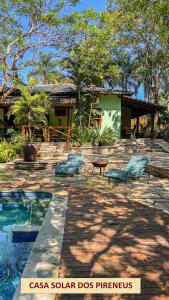 dos sillas y una piscina frente a una casa en Casas Solar dos Pireneus, en Pirenópolis