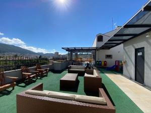 eine Dachterrasse mit Sofas und Stühlen auf einem Gebäude in der Unterkunft Minas Garden Hotel in Poços de Caldas
