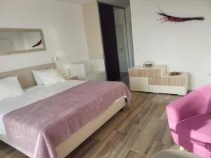 1 dormitorio con 1 cama grande y 1 silla rosa en Apartments Marlin Blue en Dubrovnik