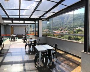a restaurant with tables and chairs and a view of a mountain at Minas Garden Hotel in Poços de Caldas