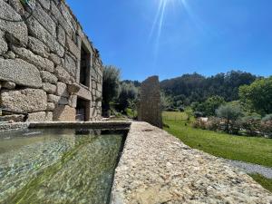 a stone wall in front of a stone building at Casa Botica - Gerês Country House in Terras de Bouro