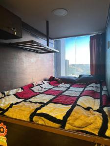 a bed with a colorful quilt in a room with a window at Petra cabin Roof top hostel in Wadi Musa