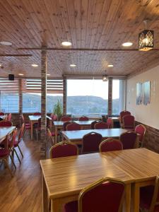 Petra cabin Roof top hostel في وادي موسى: غرفة طعام بها طاولات وكراسي ونوافذ كبيرة