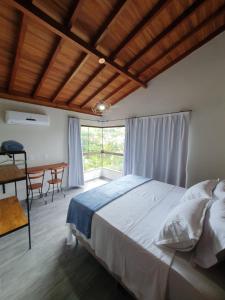 Schlafzimmer mit einem Bett, einem Schreibtisch und einem Fenster in der Unterkunft Villaggio Ronchi in Pedra Azul