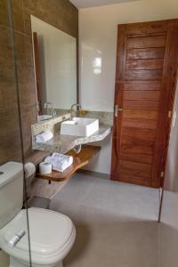 ein Bad mit einem WC, einem Waschbecken und einer Tür in der Unterkunft Villaggio Ronchi in Pedra Azul