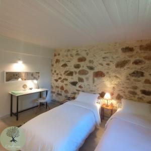 twee bedden in een kamer met een stenen muur bij DOLONAS Cosy House 
