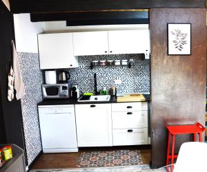 庫尼奧的住宿－La petite maison de Claire，厨房配有白色橱柜和红色凳子