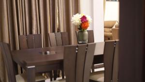 een tafel en stoelen met een vaas met bloemen erop bij Jeffston Court Apartments in Accra