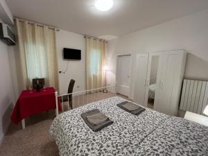 een slaapkamer met een bed en een rode tafel en een televisie bij Casa Roma rooms& apartmens in Padua